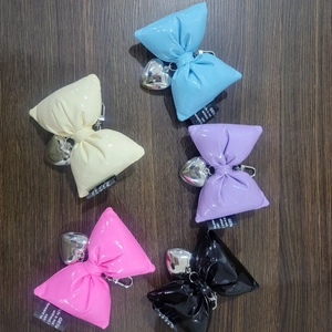 Five colorful glossy bow keychains with silver heart pendants on a dark wood background