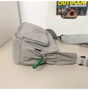 Detail of grey nylon messenger bag featuring waterproof fabric and green zipper pull cord