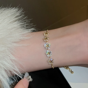 Detail of gold star flower bracelet with zircons worn on wrist with fur sleeve
