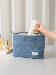 Blue denim makeup bag with white bows and heart patterns for travel skincare storage