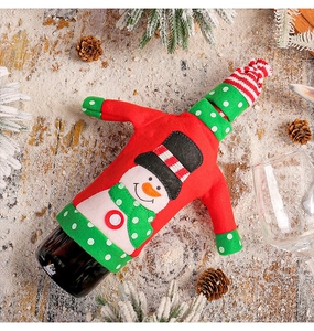 Detail of knitted snowman wine bottle cover with hat on a snowy wooden festive background