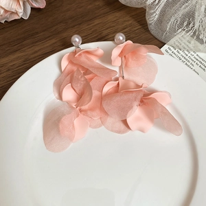 Detail of pink fabric flower earrings with pearls and glass tassels on a white tray