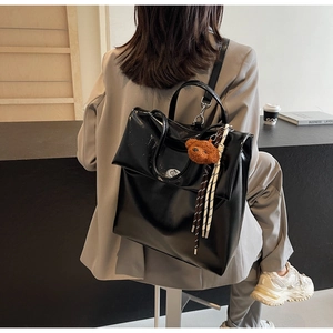 Detail of black PU leather backpack with a brown bear charm and decorative cords
