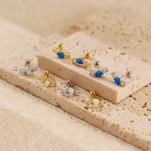 Detailed macro view of opal and zircon threaded ear studs on travertine stone