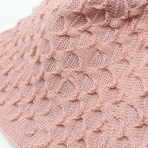 Close-up of pink knitted sun hat showing detailed wavy crochet texture and soft fabric
