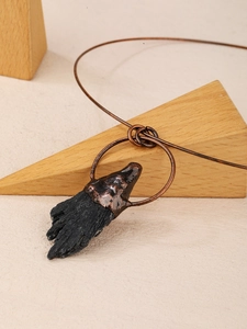 Collana con ciondolo in tormalina nera irregolare e montatura in bronzo su sfondo beige