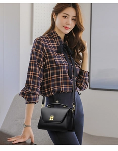 Detail of a black leather crossbody bag featuring a gold twist lock and elegant handle
