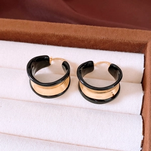 Close-up of 18k gold plated hoop earrings with black enamel detail in a jewelry box