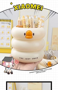 Close-up of cream duck pen holder with orange beak and THE JUDY SWAN logo base