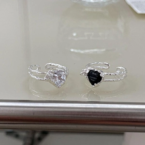 Macro detail of irregular S925 silver rings with heart-shaped black and clear gemstones