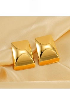Macro shot of 18K gold-plated titanium steel rectangular earrings on champagne satin