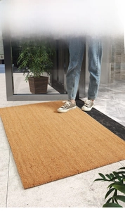 Detailed close-up of natural coir doormat texture with anti-slip fiber on tile floor