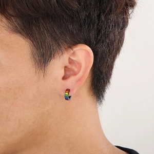 Male model wearing a black stainless steel hoop earring with rainbow stripes on white background