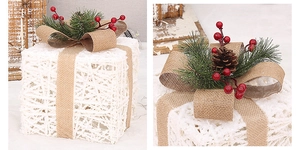 Close-up of white woven Christmas gift box with burlap bow, pine needles and pine cones