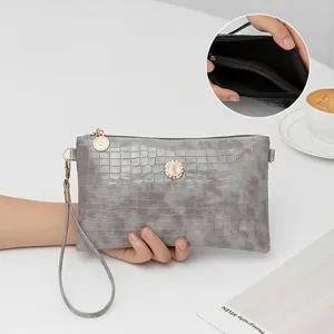 Grey crocodile-embossed clutch bag with sparkling crystal emblem and wristlet strap.