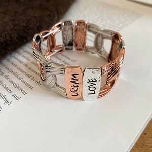 Detail of vintage stretch bracelet with DREAM and LOVE engraved on hammered metal plates