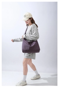 Modella che indossa una grande borsa tote in tela viola scuro con un set casual grigio