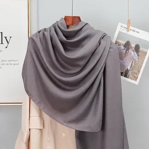 Detail of dark grey linen scarf draped over a beige trench coat for a stylish look