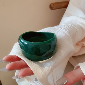 Irregular wavy thick bangle in dark green finish shown on a model hand with chic style