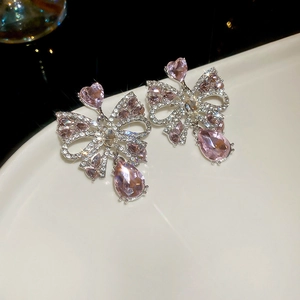 Detailed close-up of pink heart gems and bowknot earrings with pear-shaped drops