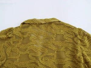 Close-up of textured fabric and back collar on a mustard yellow V-neck blouse