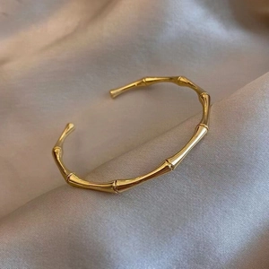 Elegant gold bamboo joint open bangle in high-gloss finish on champagne silk background