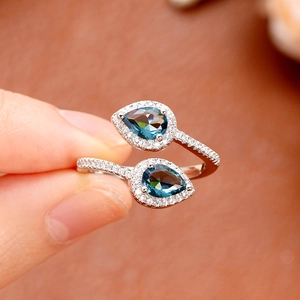 Macro detail of teardrop blue stone ring with sparkling diamond halo and silver band