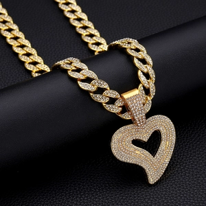 Close-up of golden Cuban chain necklace featuring a large heart pendant set with clear crystals