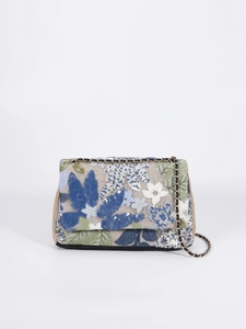 Detailed close-up of floral embroidery and sequins on a beige woven shoulder bag
