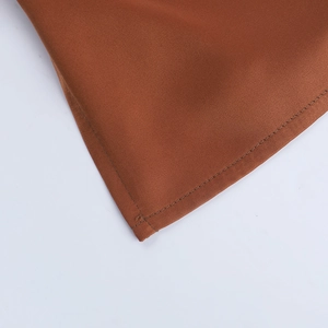 Détails macro du tissu en satin marron et des coutures fines sur le haut licou dos nu