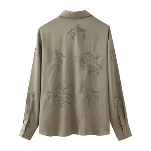 Detailed embroidery with sequins and beads on the back of a khaki satin shirt