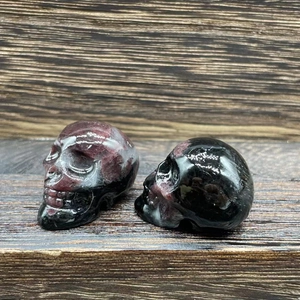 Macro shot of two polished natural stone crystal skulls with dark purple inclusions