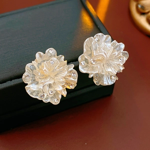 Gros plan de boucles d'oreilles fleurs plaquées or avec cristaux sur écrin à bijoux