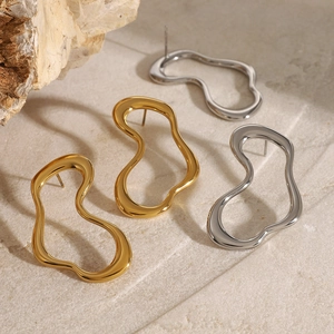 Vintage irregular hollow hoop earrings in gold and silver finish on stone background