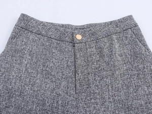 Detailed close-up of grey tweed trousers waist featuring metallic button and fine texture