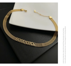 Détail du collier en maille dorée avec inscription Good Luck et fermoir mousqueton