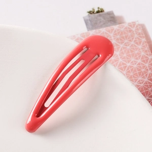 Close-up of a glossy coral pink teardrop metal BB hair clip with a smooth paint finish