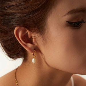 Gold hoop earrings with natural freshwater pearl star charms on professional female model