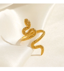 Close-up of golden snake ring featuring detailed scale texture on white silk background