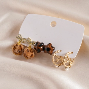 Detailed view of a 6-piece earring set with plush balls and stars on beige silk