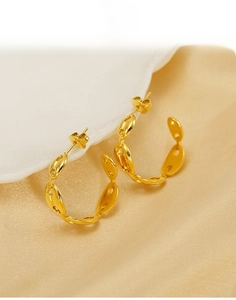 Detailed view of golden titanium steel mariner link earrings on a silk background