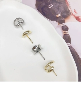 Detail view of geometric gold and silver metal hair hooks on a white ceramic tray