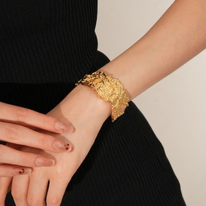 Dettaglio macro di un bracciale rigido dorato con trama lavica irregolare sulla modella