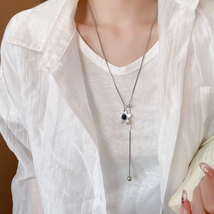 Detail of silver long Y-shaped necklace featuring flower pendant with pearl and tassel