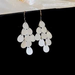 Detail of white teardrop layered fringe earrings with gold-tone hooks and pearly finish