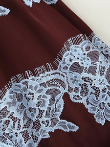 Détail du tissu satiné bordeaux avec une bordure délicate en dentelle bleu clair