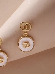Macro shot of gold double-ring earrings featuring elegant white mother of pearl inlay