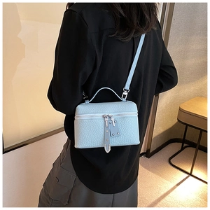Detail view of light blue textured leather bucket bag with silver zipper and handle