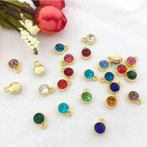 Colorful 7mm alloy crystal pendants with gold plating scattered on white fabric