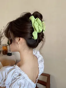 Detail of bright green pleated fabric scrunchie worn on a bun for an elegant hair styling look